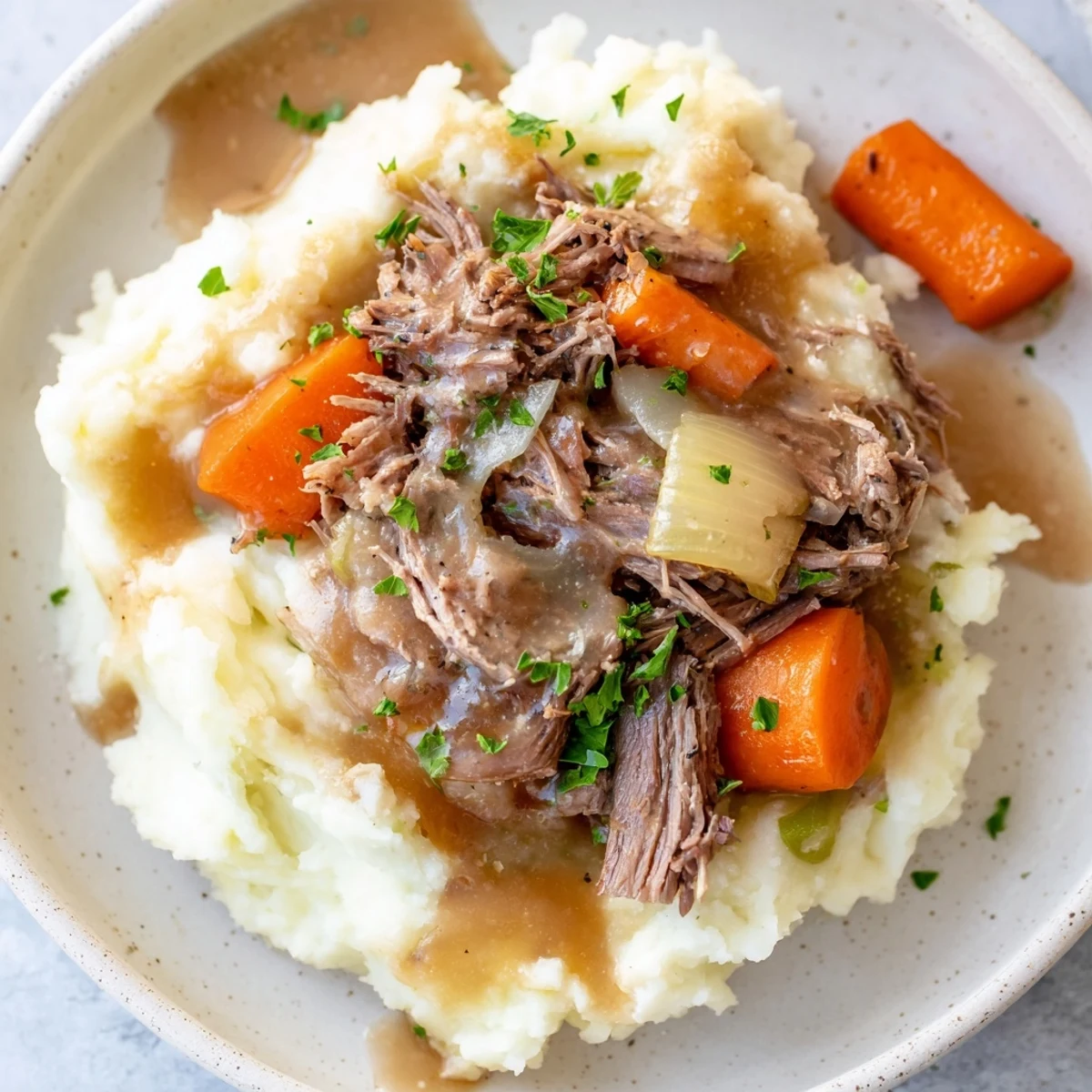 Fork-tender beef with vegetables, pictured alongside fluffy mashed potatoes in Slow Cooker Pot Roast.