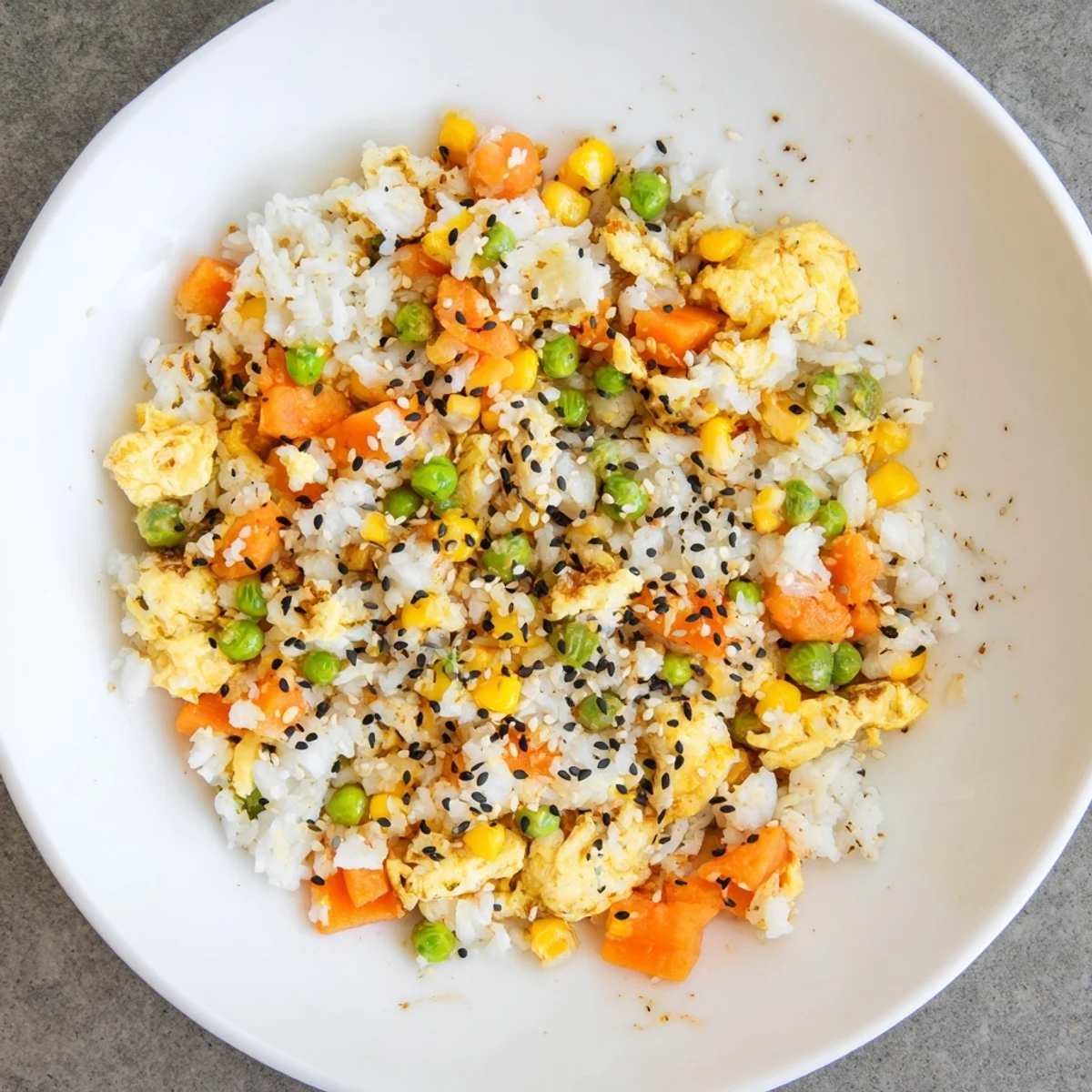 A steaming bowl of colorful Frozen Veggie Fried Rice, glistening with soy sauce and sprinkled with fresh green onions.