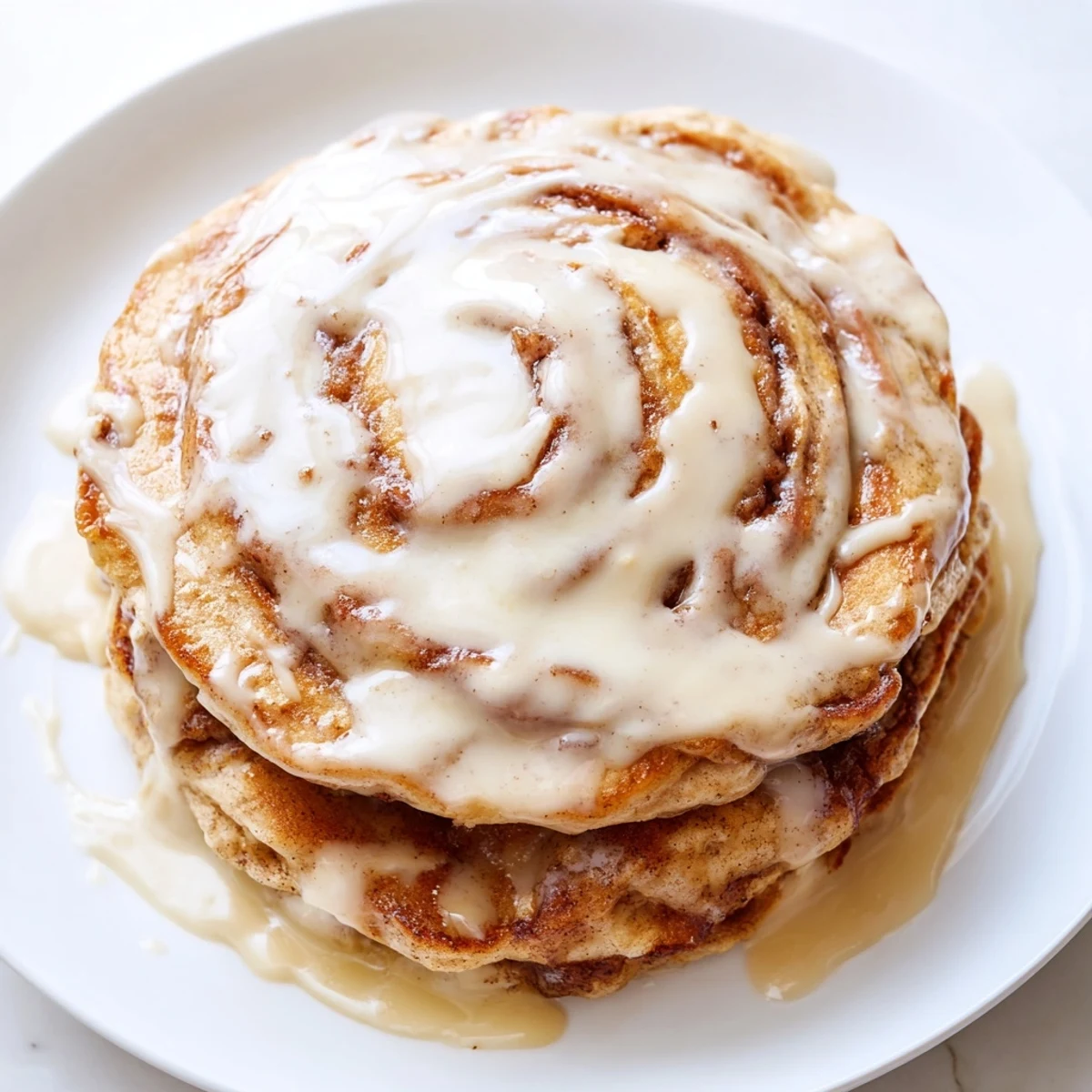 Warm, homemade Cinnamon Roll Pancakes: light, airy, and topped with irresistible cream cheese glaze.