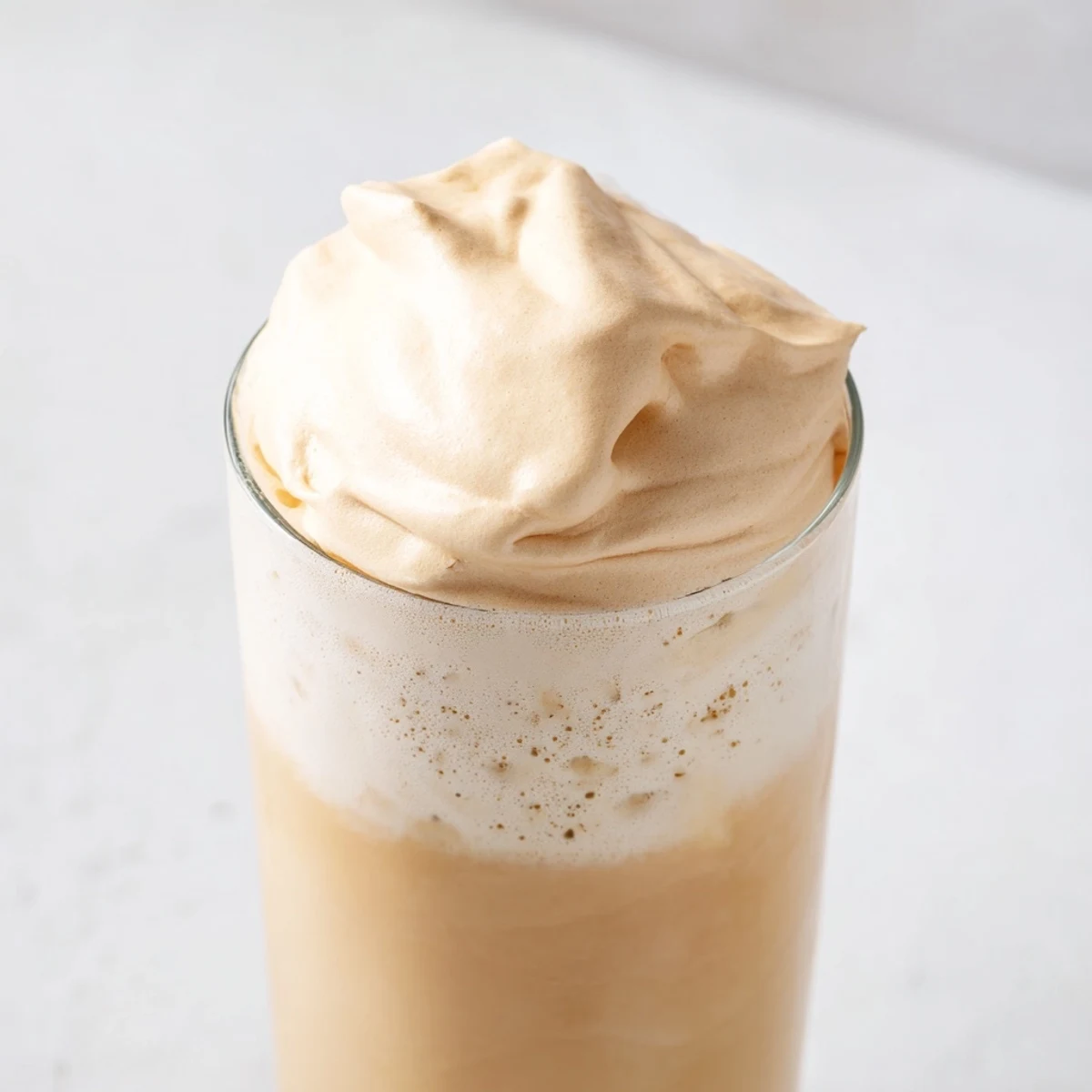 Fluffy whipped Dalgona coffee, a creamy Korean-inspired treat with cloud-like foam floating on milk.