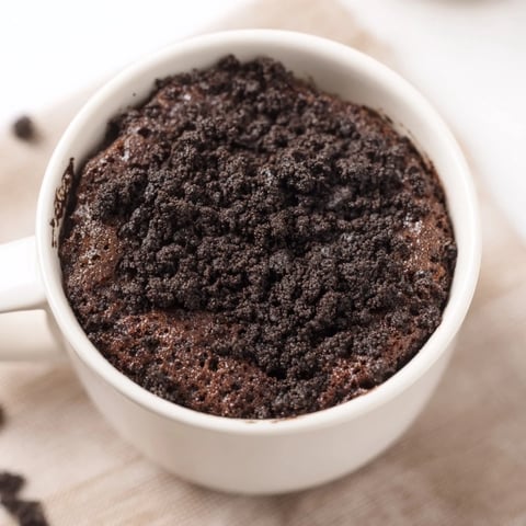 Steaming Oreo Mug Cake, a personal dessert, looks moist and chocolatey in a white mug.