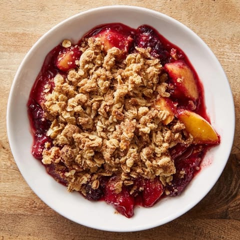 Oven-baked fruit crisp with mixed berries, a comforting dessert with a crispy oat crust.