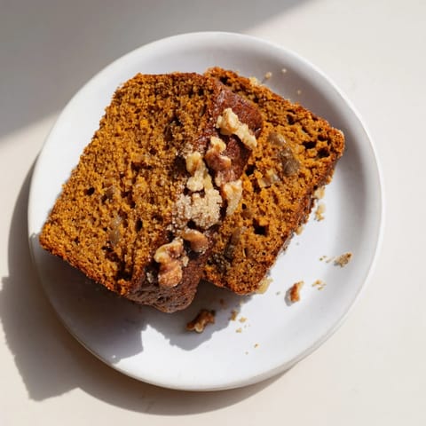 Freshly baked pumpkin bread loaf, its moist crumb hinting at cinnamon and nutmeg flavors.