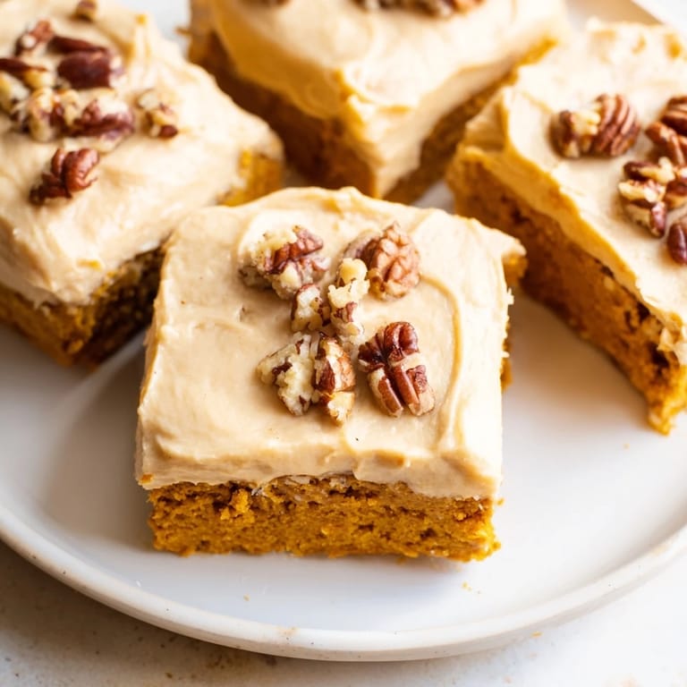 A close-up of delicious pumpkin bars with fluffy brown sugar frosting, a perfect dessert.