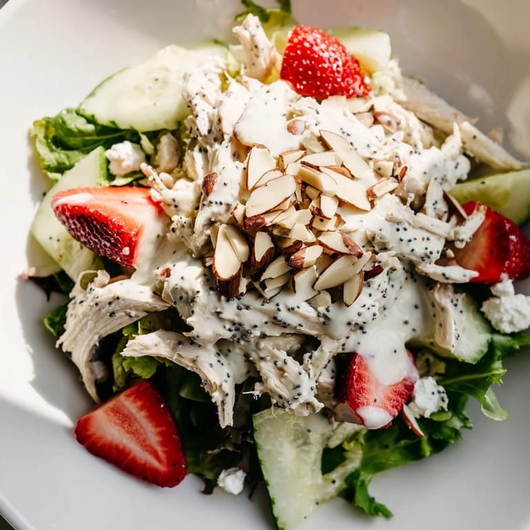 This colorful Strawberry Poppy Seed Chicken Salad features a creamy, tangy poppy seed dressing drizzled over mixed greens and topped with crunchy toasted almonds and optional feta.  