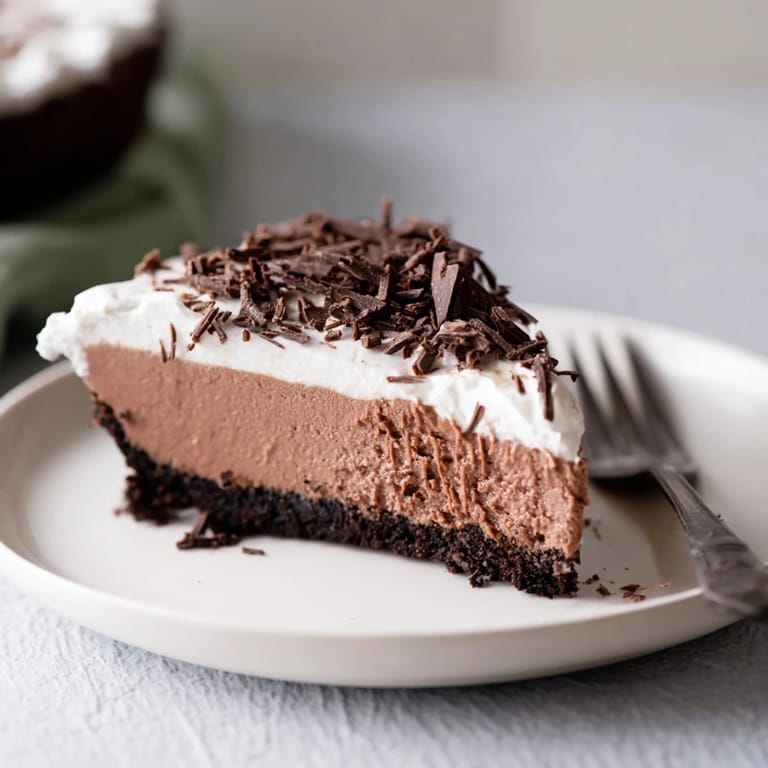 A smooth chocolate cheesecake slice on a white plate, ready to serve with fresh berries for a sweet, tangy contrast.