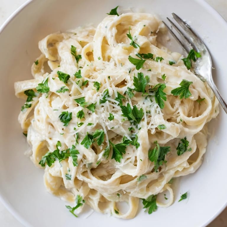 Tender Easy Creamy Cauliflower Alfredo pasta is served with grated Parmesan, inviting a comforting Italian-inspired dinner.
